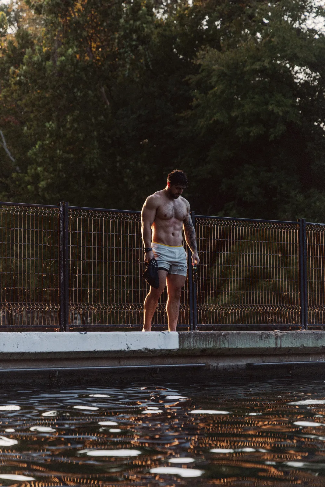 Swimmer at the edge of an outdoor pool at sunset